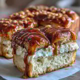 A golden-brown loaf of Caramel Cream Cheese Bread is cut open, revealing a rich cream cheese center and sweet caramel ribbons.