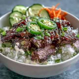 Colorful Korean Beef Power Bowl with spicy jalapeños and creamy sriracha mayo drizzle, served as a complete meal.