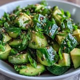 Fresh smashed cucumber avocado salad dish glistening with sesame oil dressing.