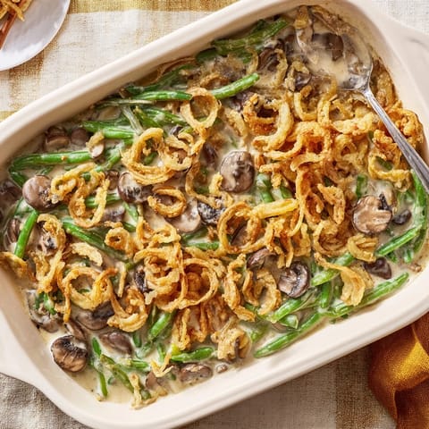 Green Bean Casserole served in a white baking dish, bubbling with a rich, creamy sauce and golden topping.