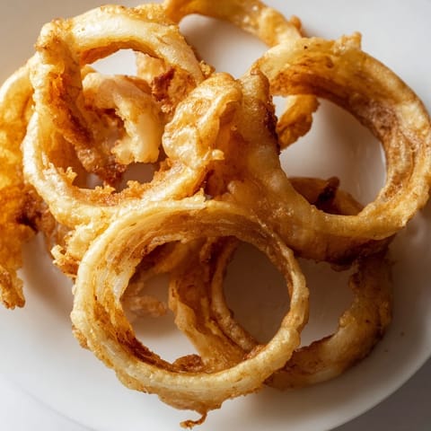 Golden, crispy Onion Rings coated in a light, bubbly batter, served hot with a side of creamy ranch dip.