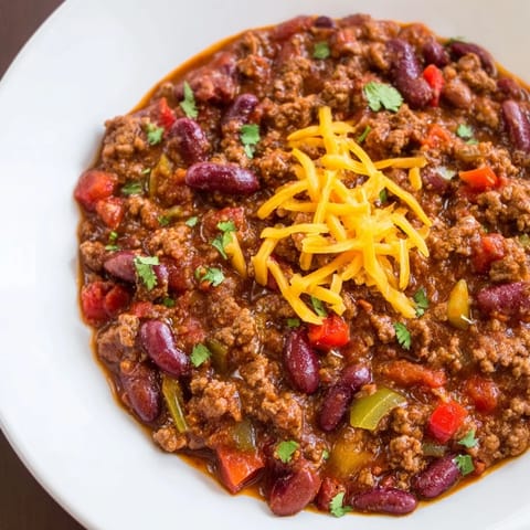 Hearty bowl of chili con carne with beans, avocado, and green onions.