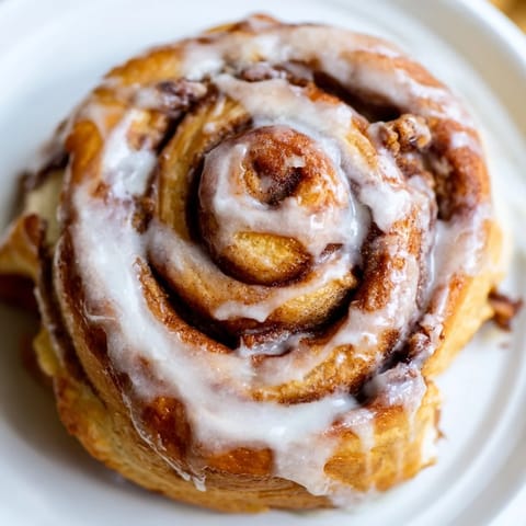 Freshly baked Cinnamon Rolls with a vanilla glaze, arranged warm in a baking dish with a side of milk. 