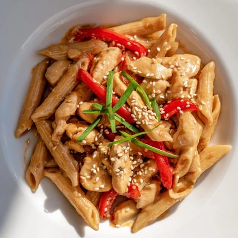 Hearty Sweet Chili Chicken Pasta served in a white bowl, garnished with cilantro and sesame seeds, ready for a weeknight dinner.  