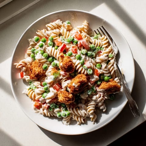 Golden brown panko-crusted chicken pieces are tossed with rotini pasta, sweet peas, and diced red bell peppers in a creamy ranch dressing, creating a delicious Crispy Chicken Ranch Pasta Salad.
