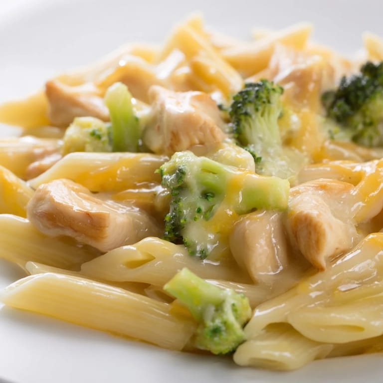 Steaming bowls of Chicken Broccoli Cheddar Pasta feature al dente penne coated in velvety cheddar, with juicy chicken and fresh broccoli for family dinner.