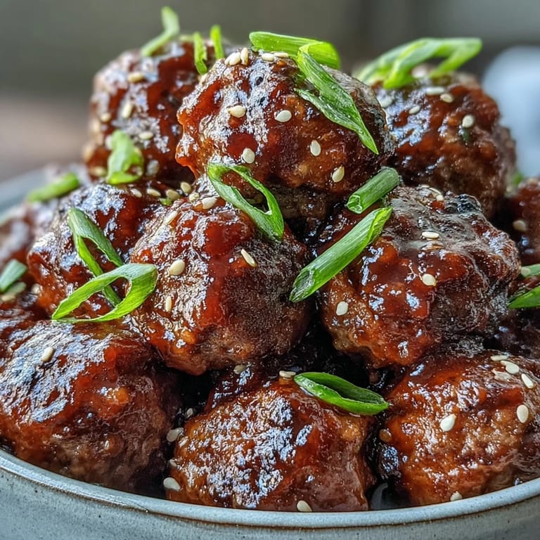 Glazed sweet and sour crock pot meatballs garnished with green onions and sesame seeds, served warm over steamed white rice.