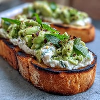 Vibrant fava bean and mint bruschetta on smoky grilled sourdough, a spring appetizer.